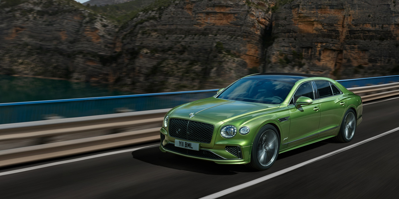 Bentley Köln Bentley New Flying Spur Speed v8 hybrid sedan driving dynamically on a mountain road in Tourmaline Green paint