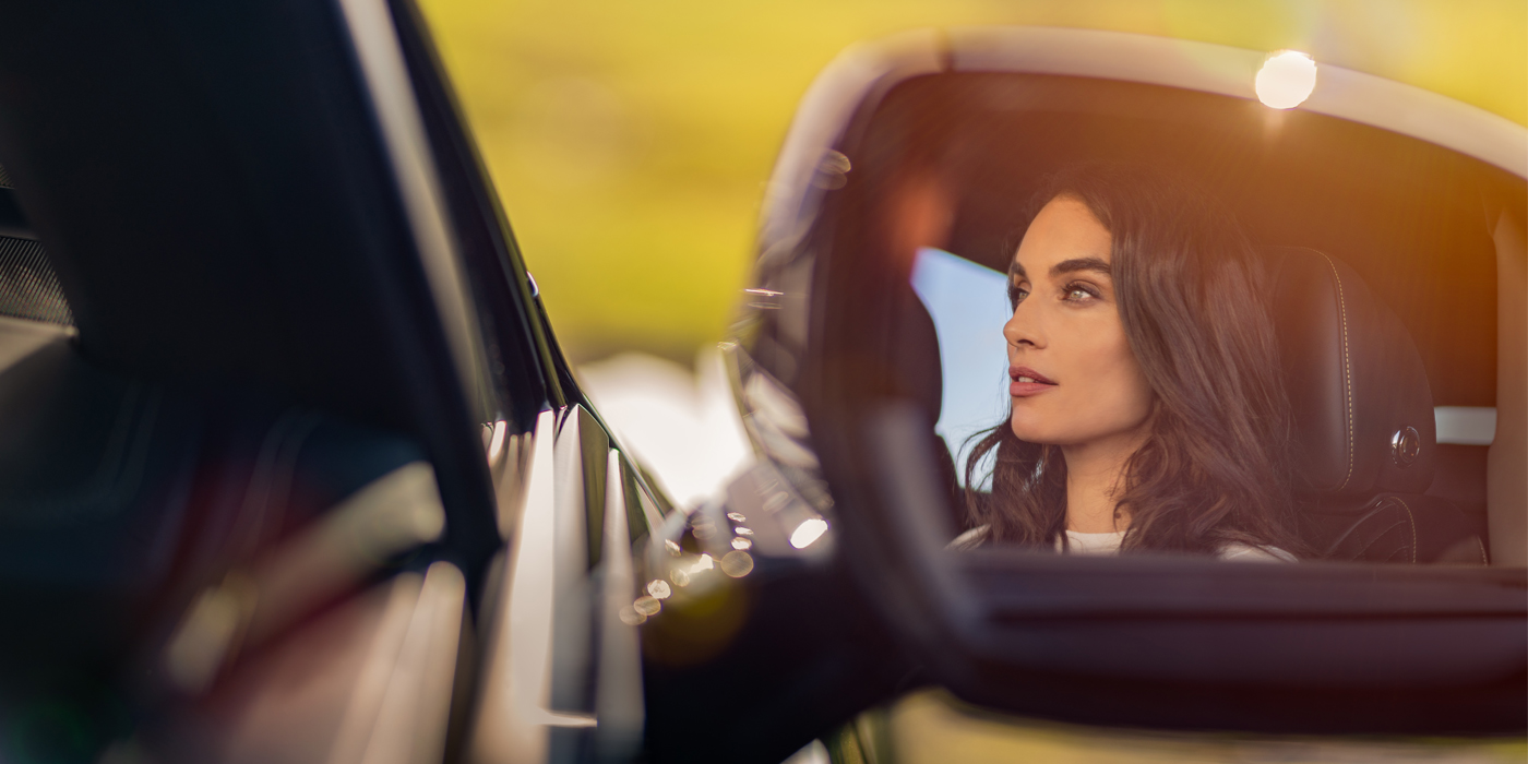 Bentley Köln profile of dark haired woman's face in mirror of Bentley car in sunlight