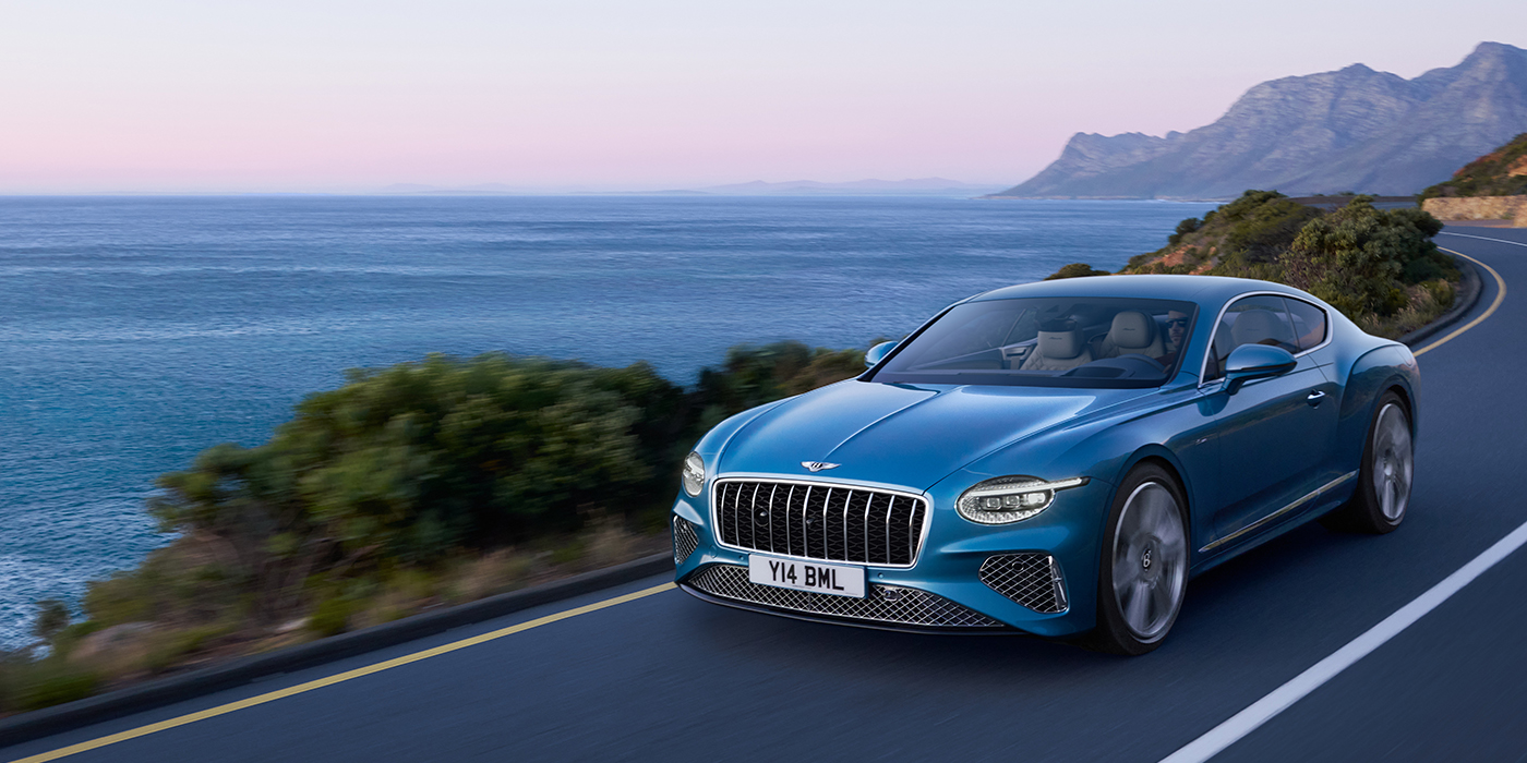 Bentley Köln New Bentley Continental GT Azure coupe in Light Windsor blue paint with 22 inch Azure wheels and chrome grill, driving dynamically by the sea