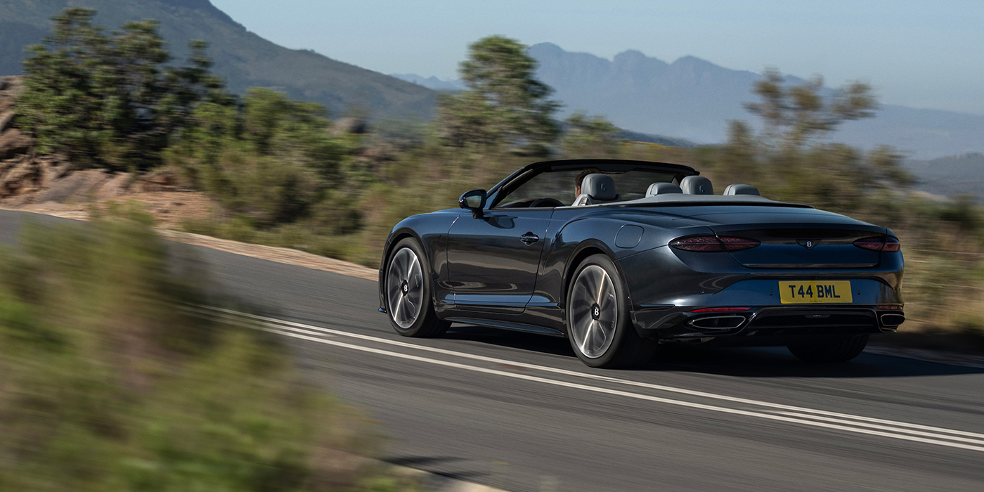 Bentley Köln Bentley Continental GTC S convertible in Thunder blue paint rear 3/4 driving on mountain road