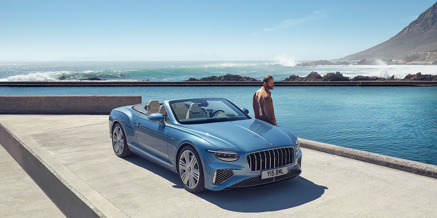 Bentley Köln New Bentley Continental GTC Azure convertible front view in Light Windsor blue paint with 22 inch ten spoke wheels parked by the sea in the sunshine