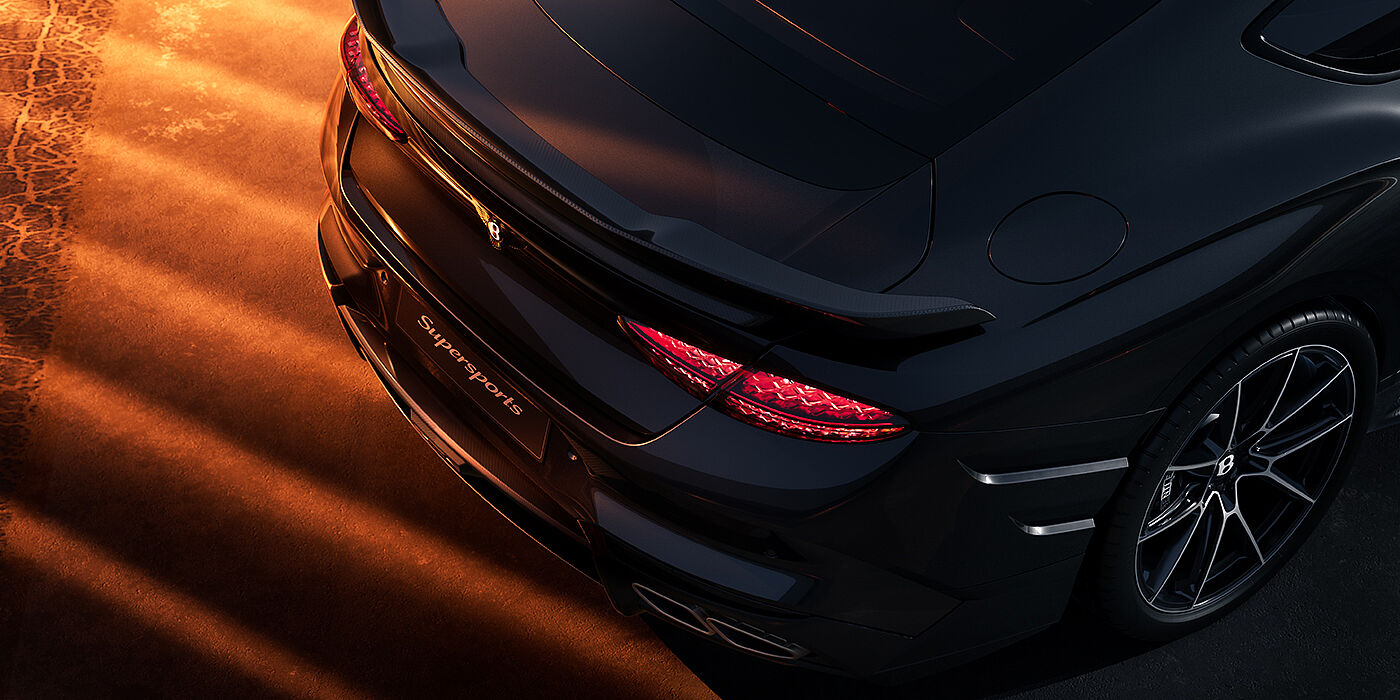 Bentley Köln Bentley Supersports rear overhead view showing illuminated rear lamps and Supersports Forged Alloy wheel in Anthracite paint against a dark grey and red background