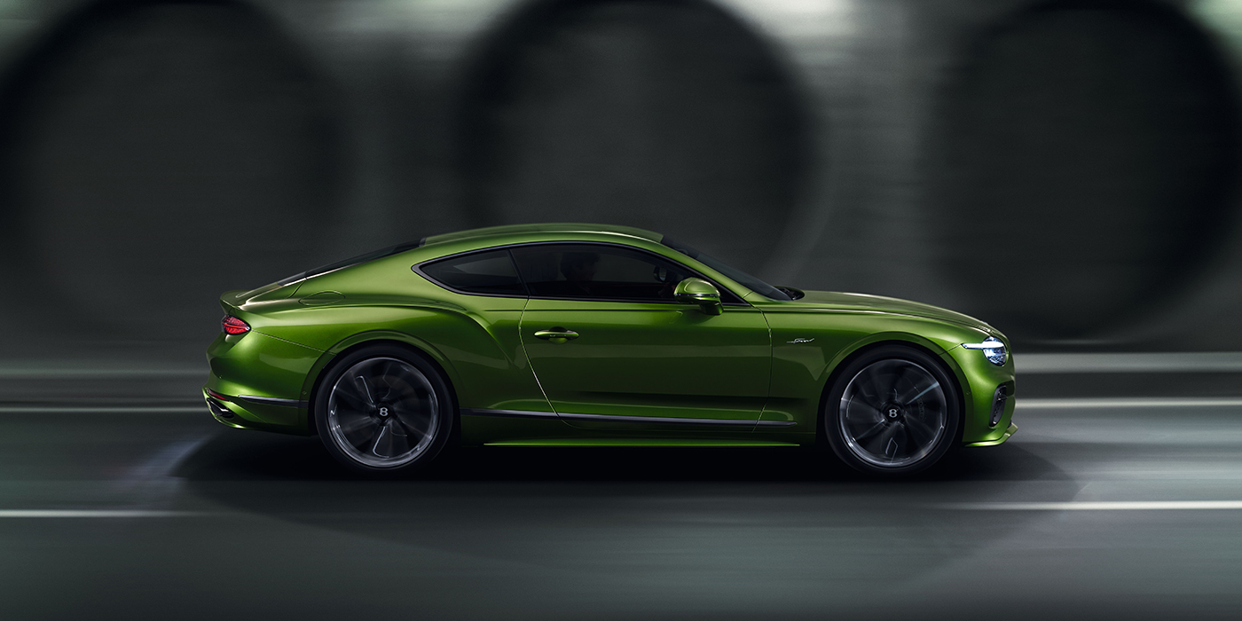 Bentley Köln Bentley Continental GT coupe in Tourmaline Green paint driving in profile on a dark road